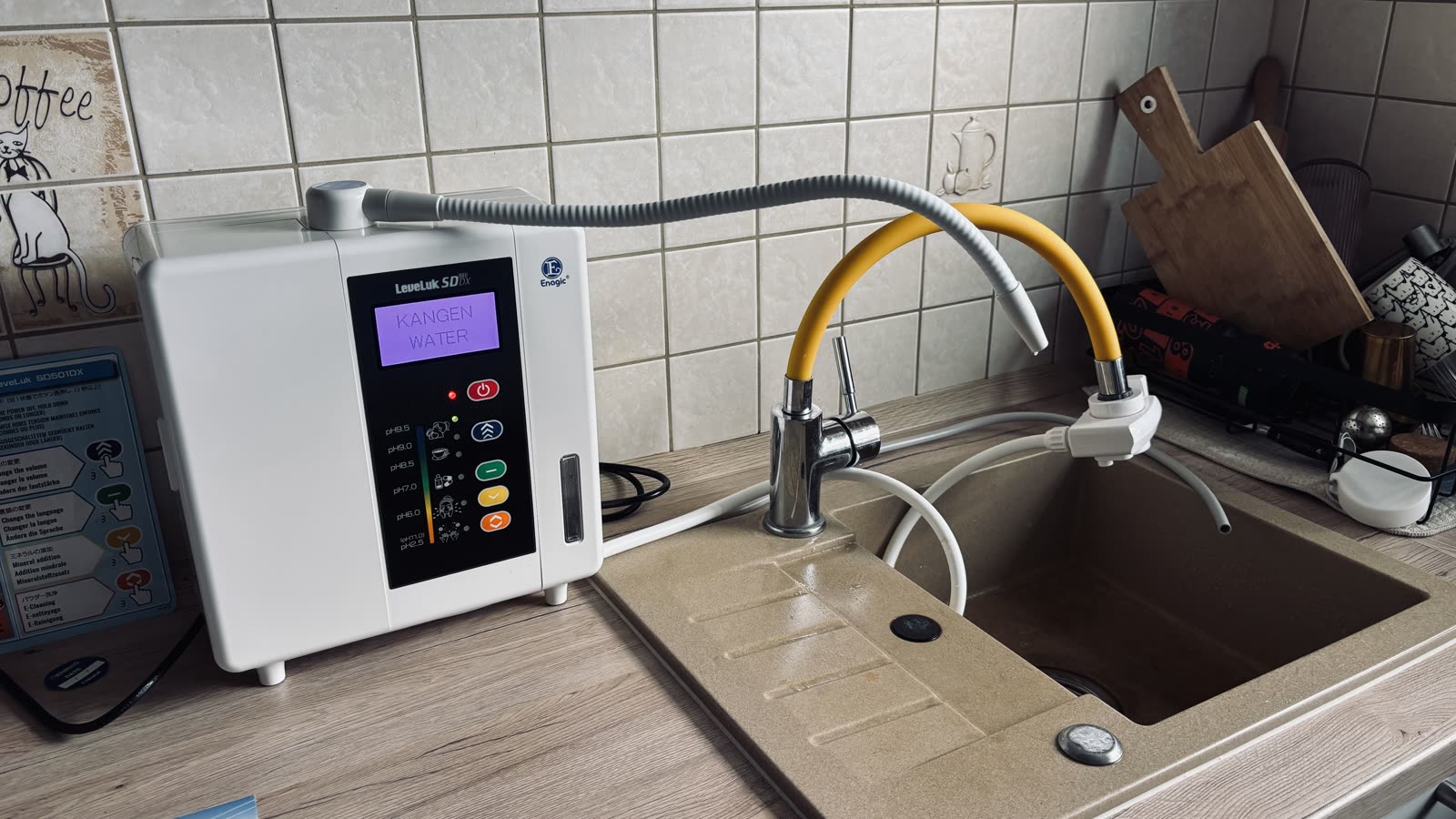 Jonizator wody Kangen Leveluk SD501DX zamontowany na blacie kuchennym, podłączony żółtym wężem do baterii nad zlewem